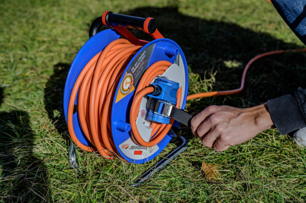 En person som använder en Husvagns kabelvinda med 25m H07RN-F 3x2,5mm Orange på gräset.