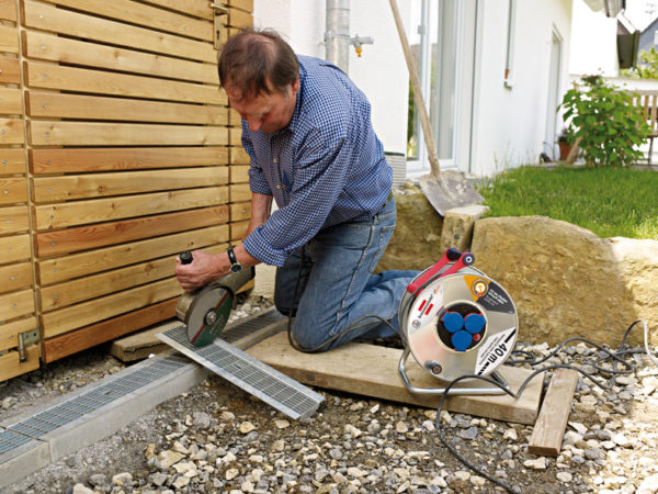 A man using a grinder to Garant kabelvinda 40m för tuff användning med 3 uttag 230V metal.