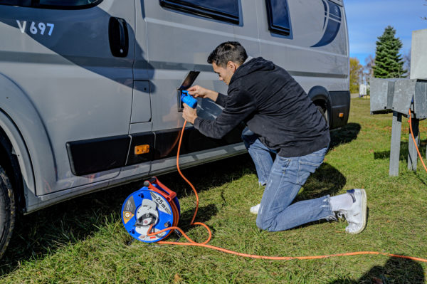 En man använder en Husvagns kabelvinda för att koppla en generator till en husbil.